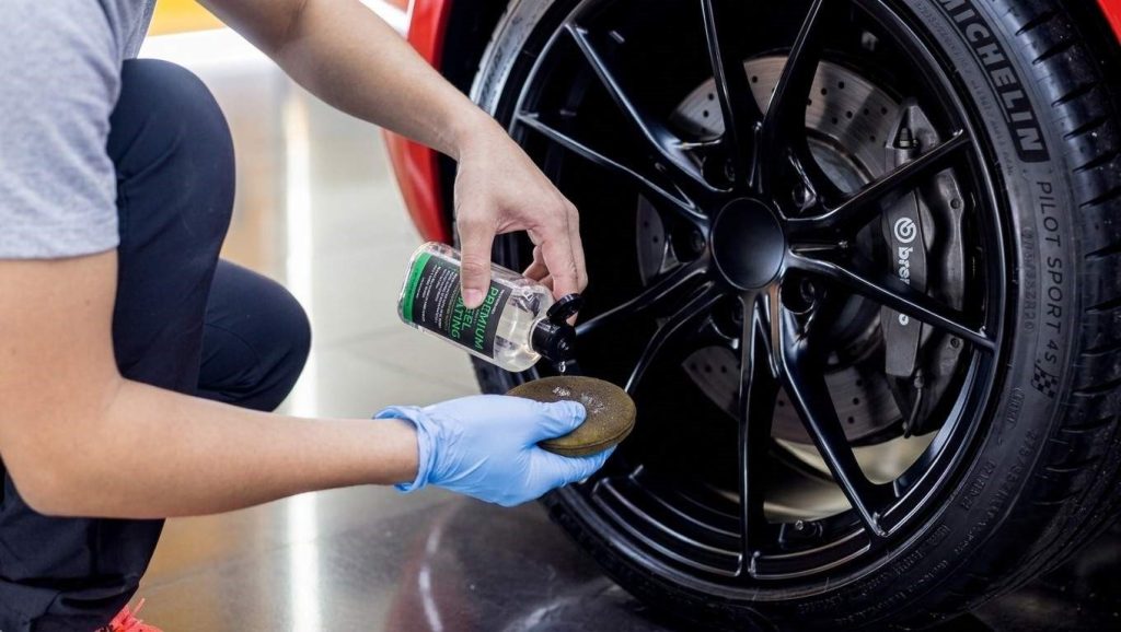 Close-up of an alloy wheel and brake caliper being treated